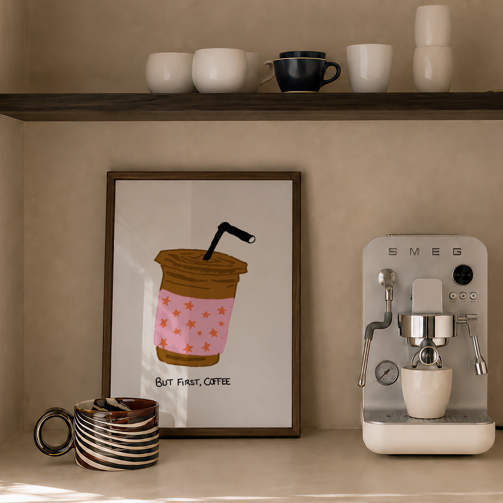 A styled coffee corner with a framed coffee cup illustration on the wall, a countertop espresso machine, stacked ceramic cups on a shelf, and a candle.