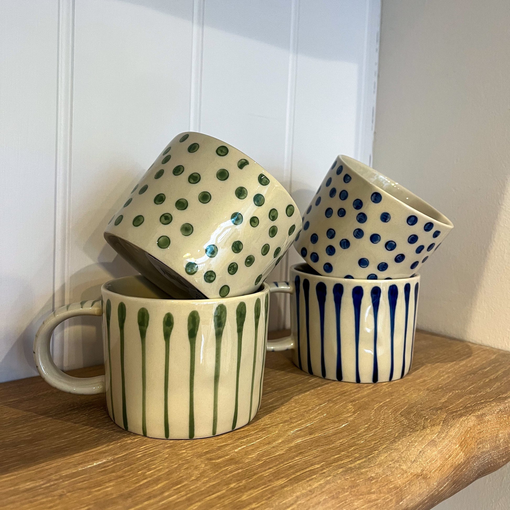 Four ceramic mugs with different patterns on a wooden surface.