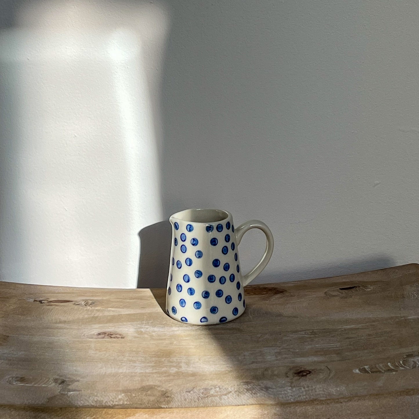 Ceramic mug with blue polka dots on a wooden surface with a blurred background